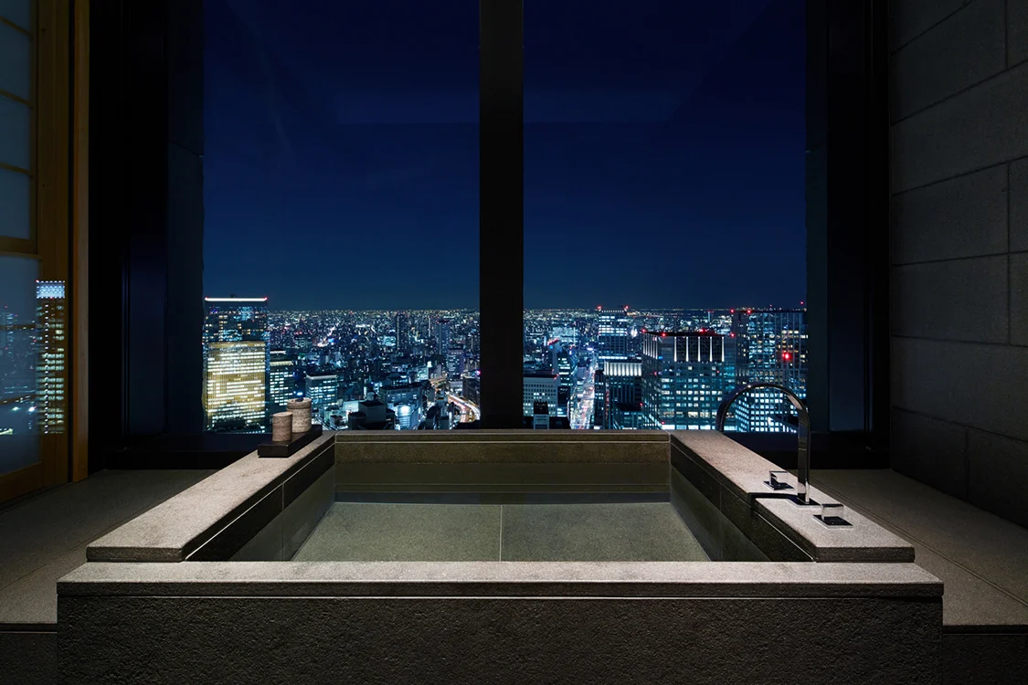 Deep furo soaking tub beside a window overlooking Tokyo