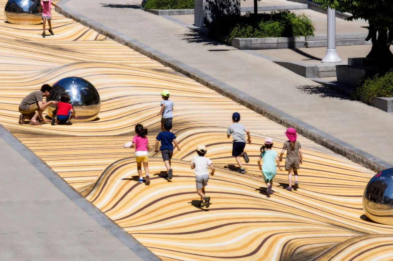 Children running across the optical-illusion street mural