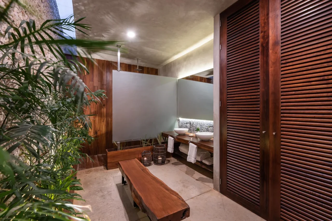 Bathroom with warm wood accents, plants, a skylight and backlit mirror