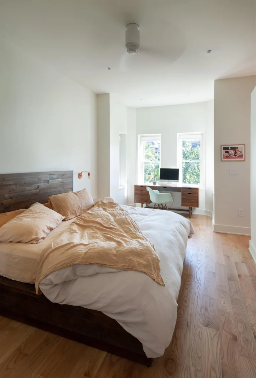 Bright bedroom with white walls and a home office by the windows