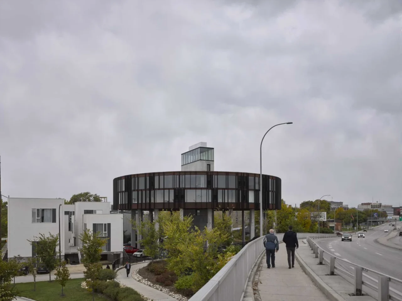 Round building with two levels of wedge-shaped apartments lifted above the ground