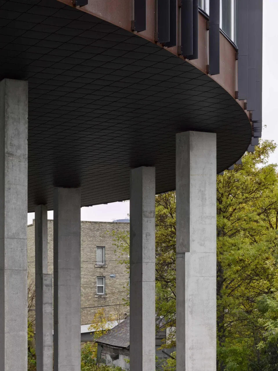 Concrete columns supporting the raised round apartment building, with parking underneath