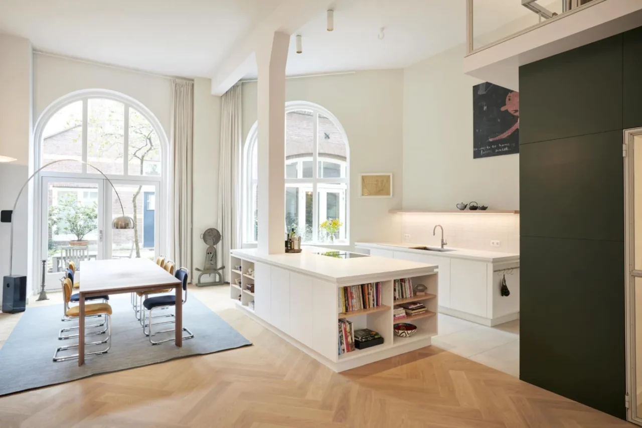 White kitchen island built around a tall structural column in an Amsterdam factory loft