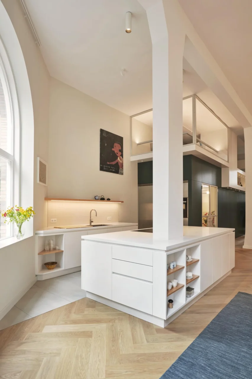 Large white island wrapping the column, with drawers and open shelving