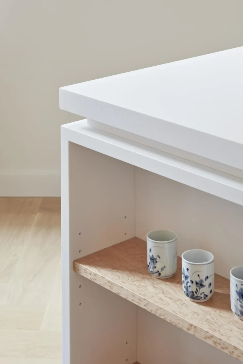 Open wood-finish shelving in the side of the white kitchen island