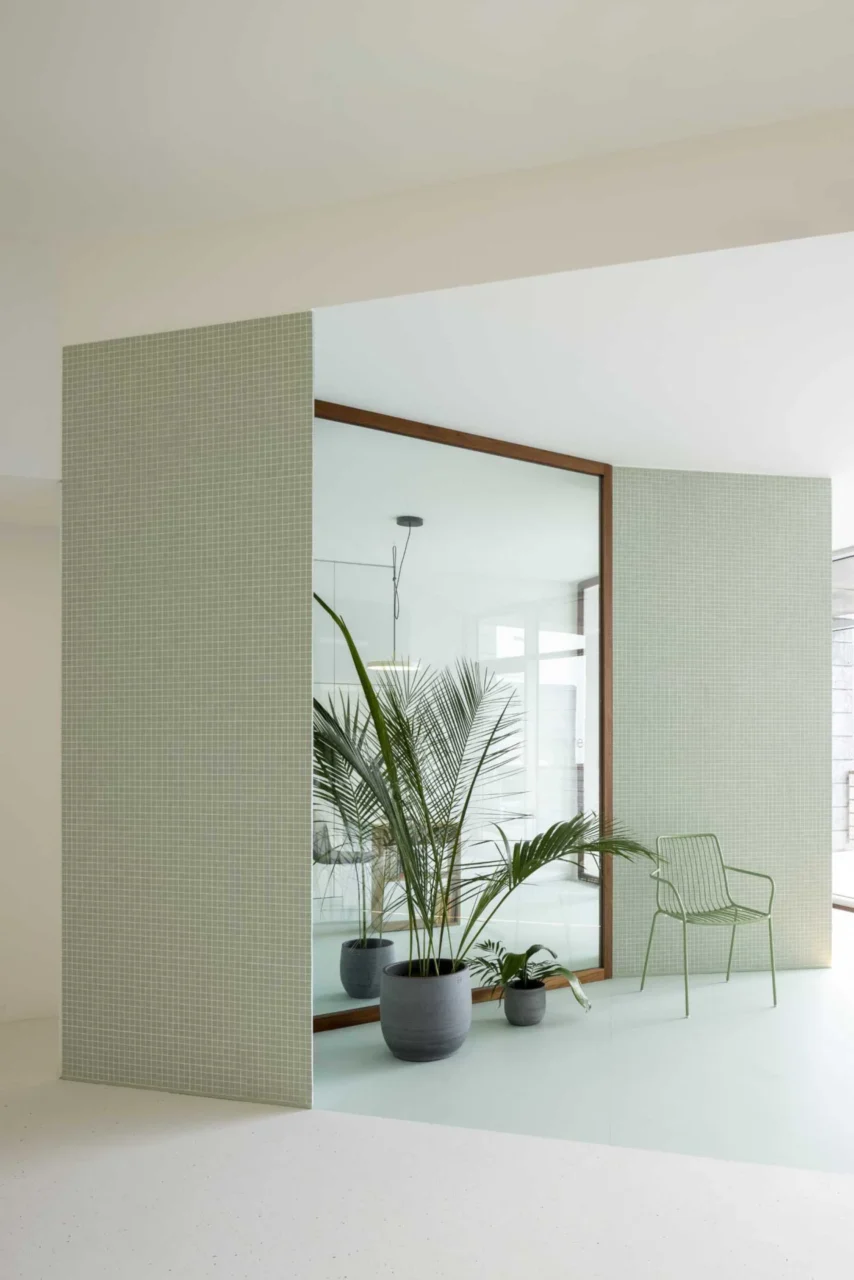 Waiting area with small square pastel green tiles, plants and matching furniture