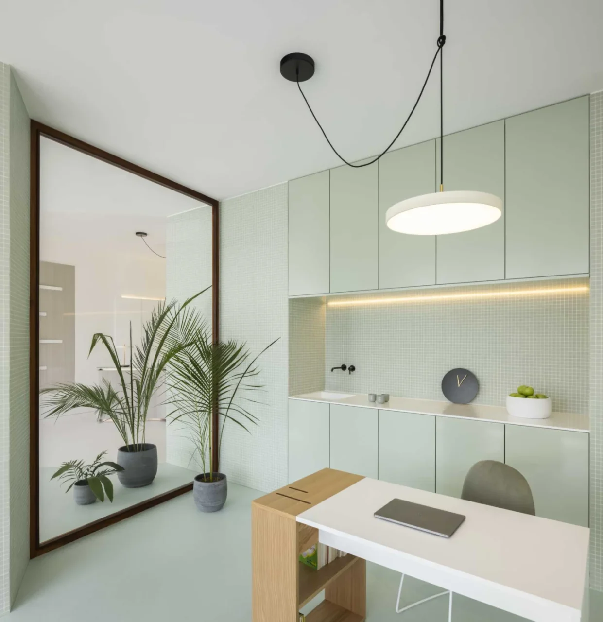 Office storage wall with pastel green cabinets, a small sink counter and tiled backsplash