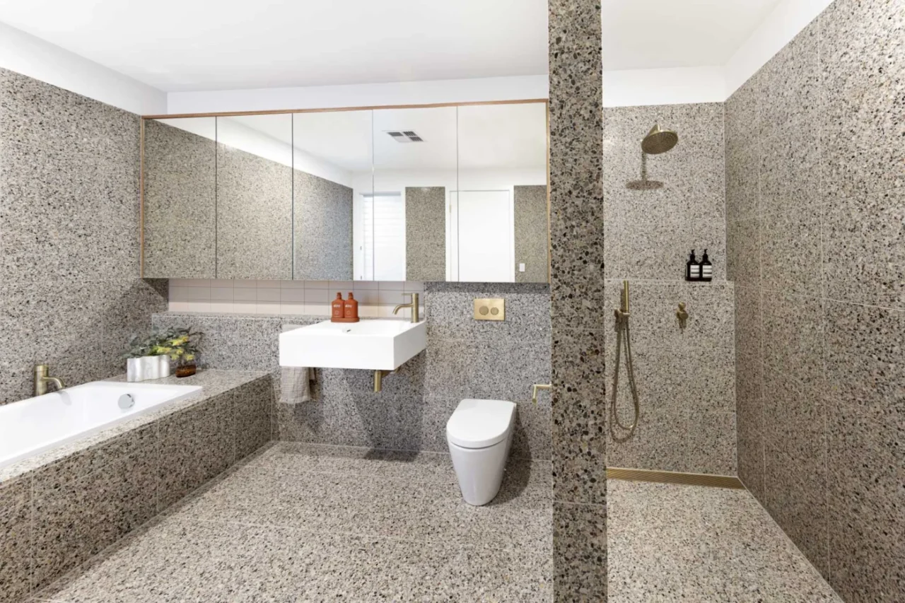 Tiled primary bathroom with a built-in bathtub and a shower behind a solid wall
