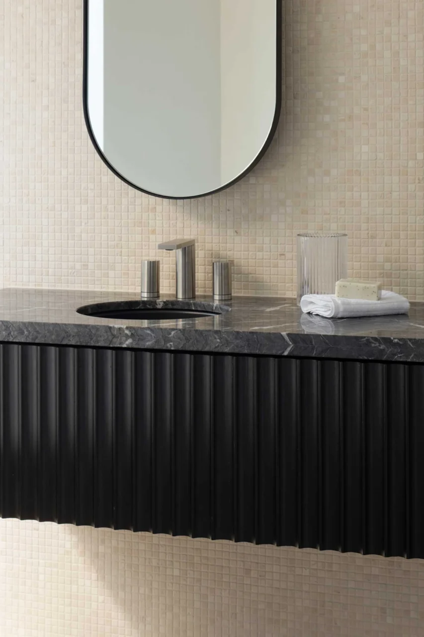 Floating timber and stone vanity against travertine mosaic tiles