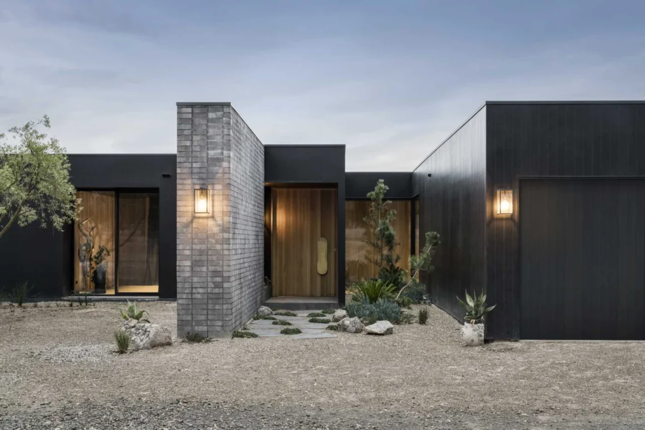 Vertical timber front door with a brass handle set in the black exterior