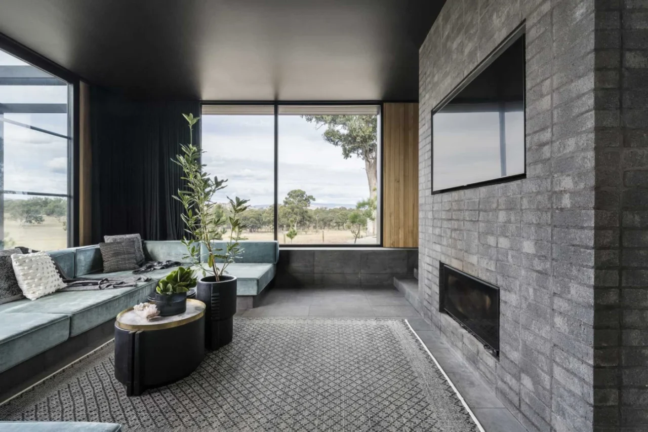 Living room on a lower level with a brick fireplace and recessed television