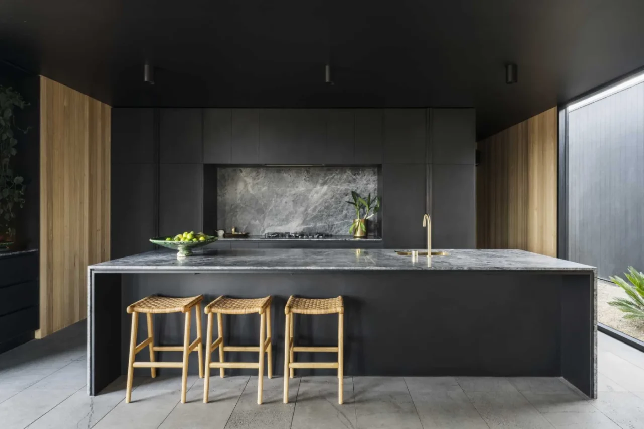 Kitchen with minimalist black cabinetry, brass accents and a large island