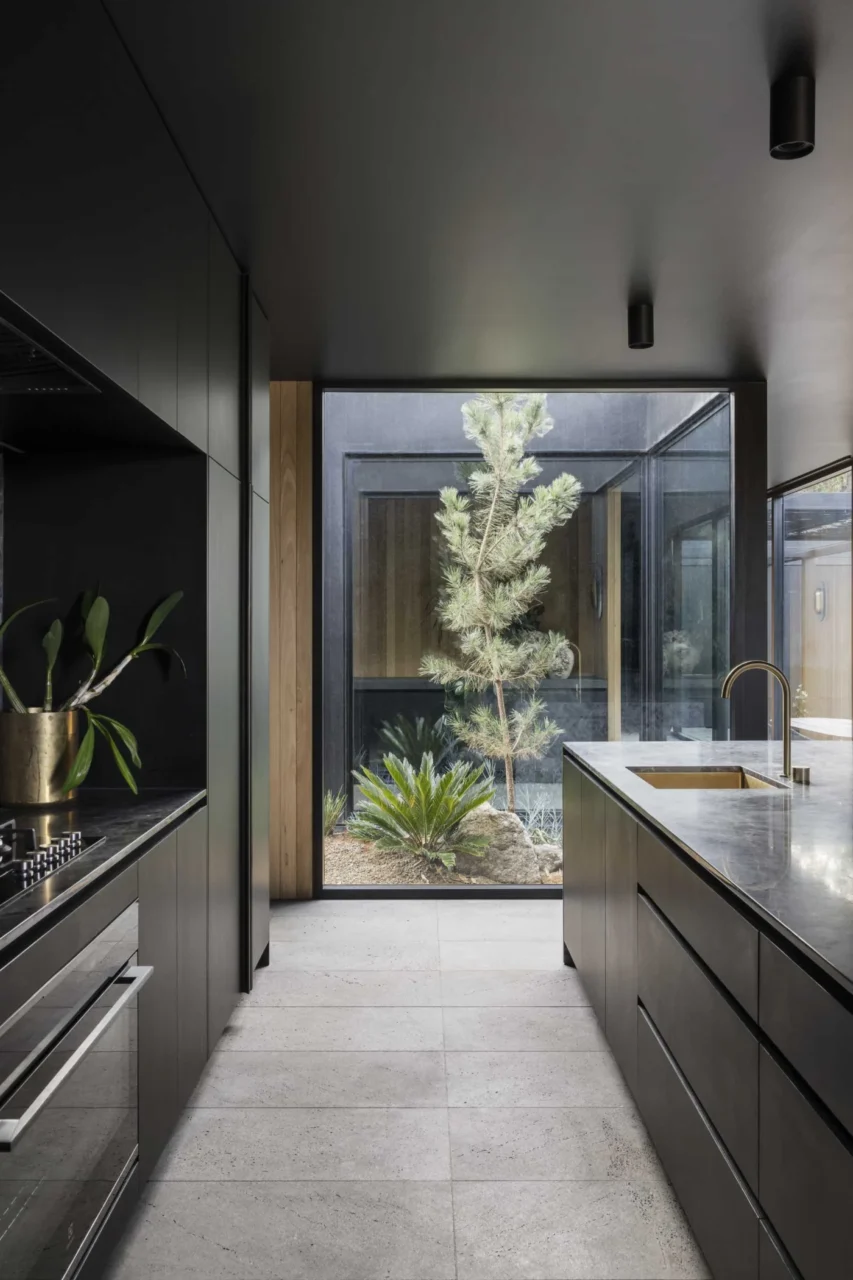 Window at the end of the kitchen island framing a small garden