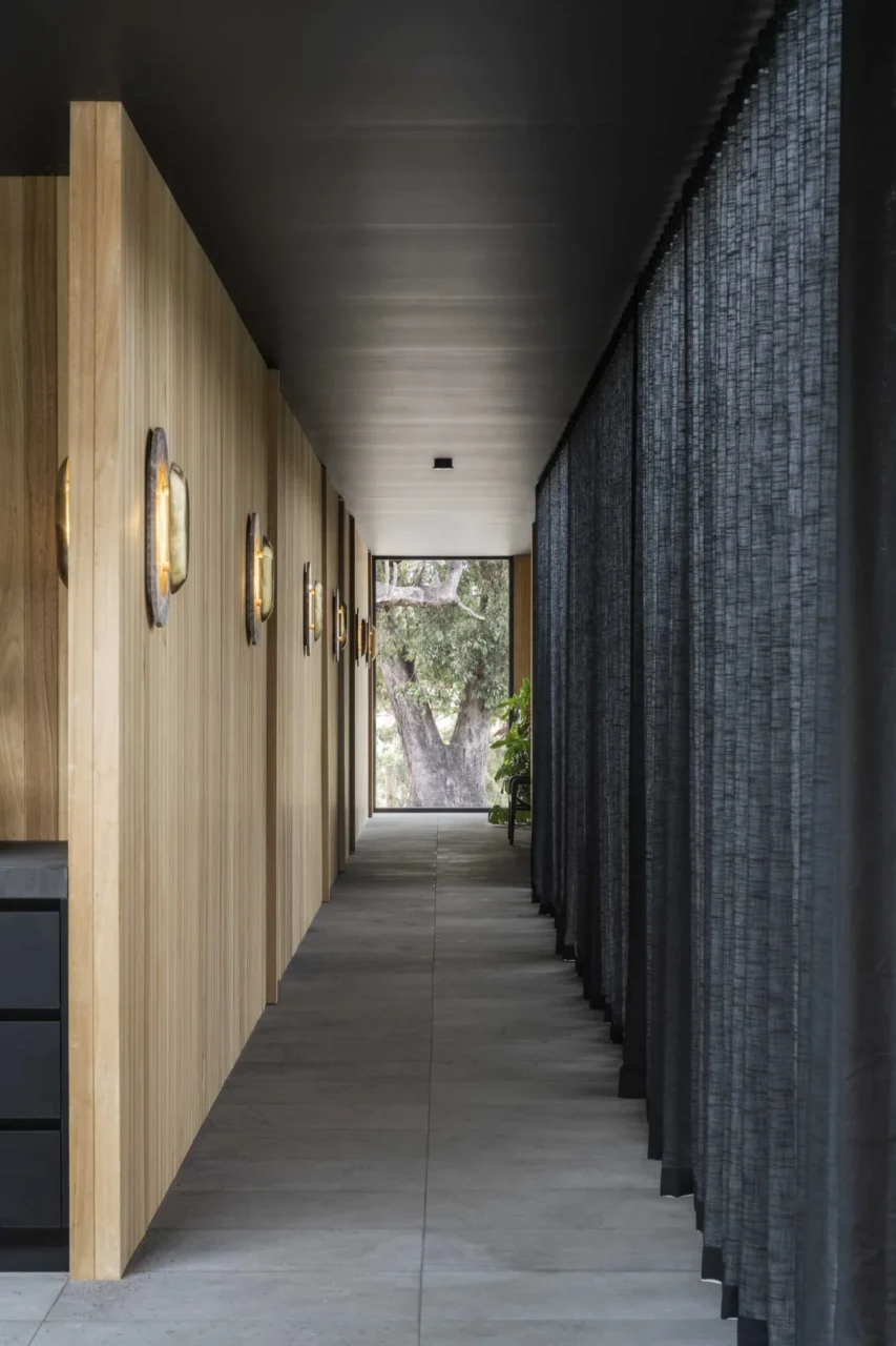 Long hallway with a black ceiling, tile floor and vertical timber wall