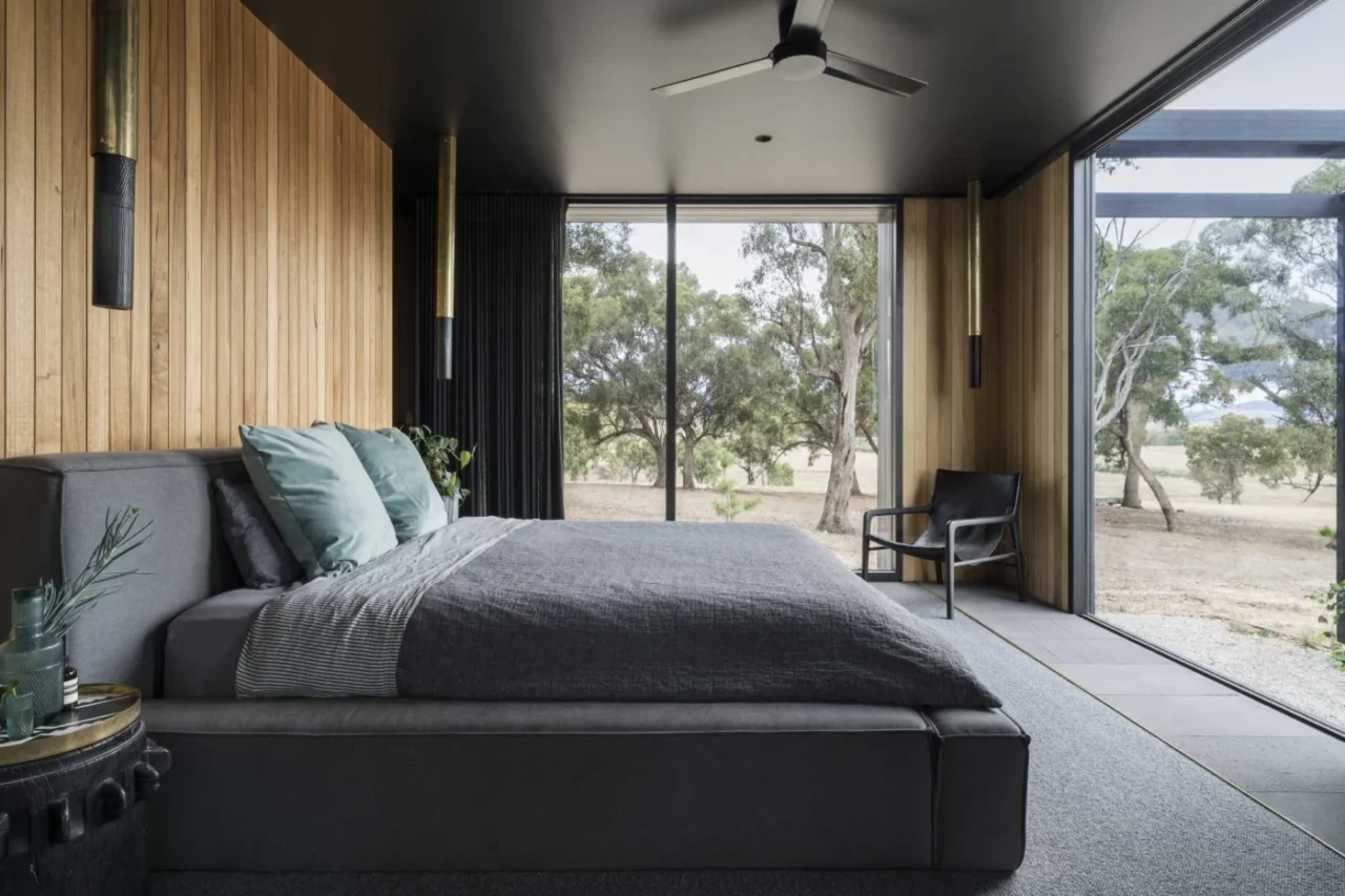 Bedroom with a vertical timber wall where the tile floor changes to carpet