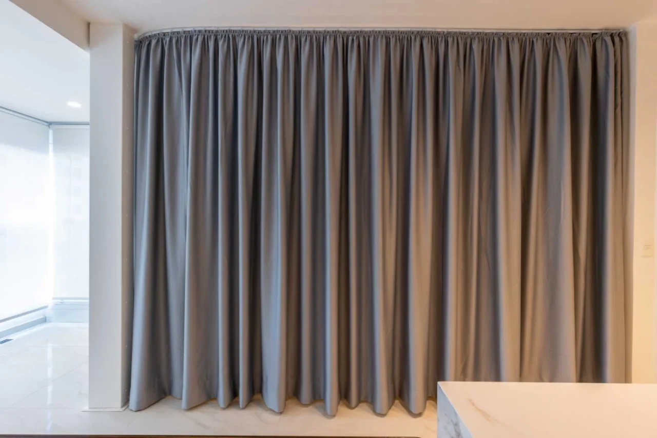 Bedroom with curtains drawn back, opening onto the living space