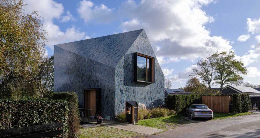 blue-tiles-cover-the-exterior-of-this-house-with-a-twisted-roof