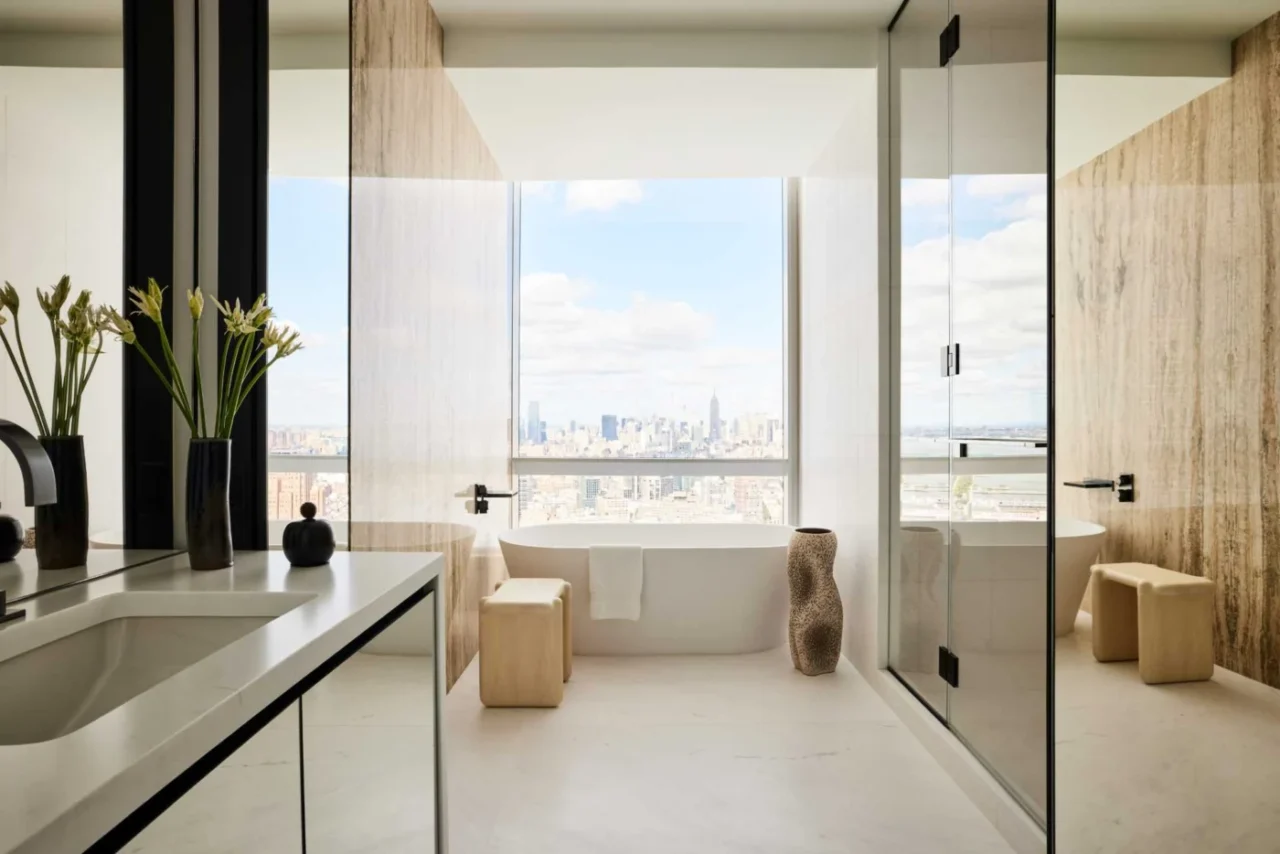 Freestanding bathtub in front of a window with city views