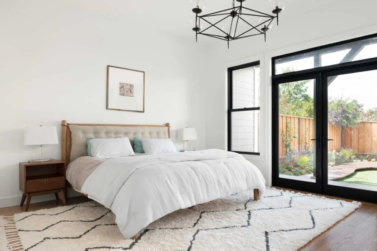 Bedroom with black-framed windows and doors facing the rear yard