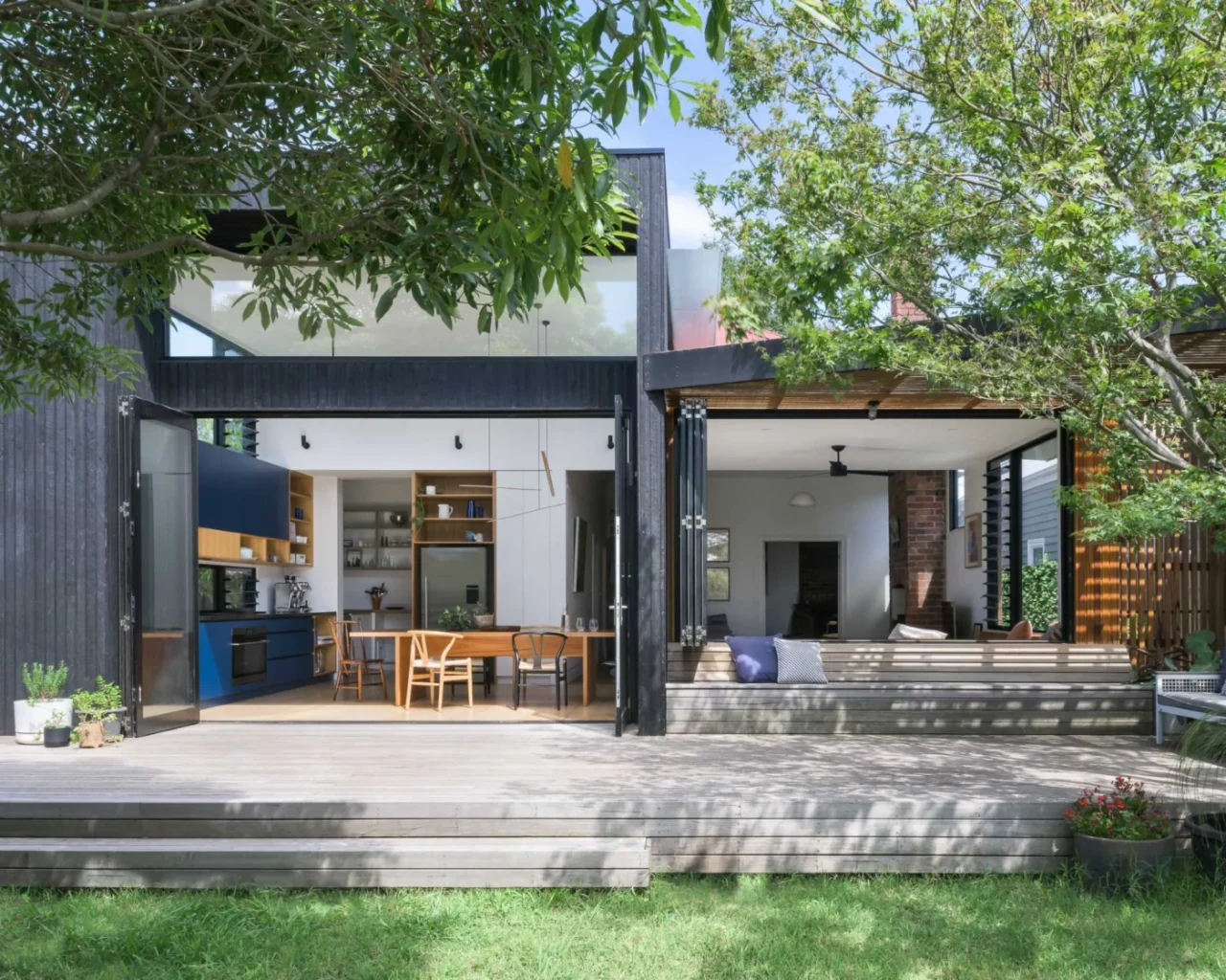 Dark-clad rear extension of an Edwardian home in Victoria opening onto a timber deck