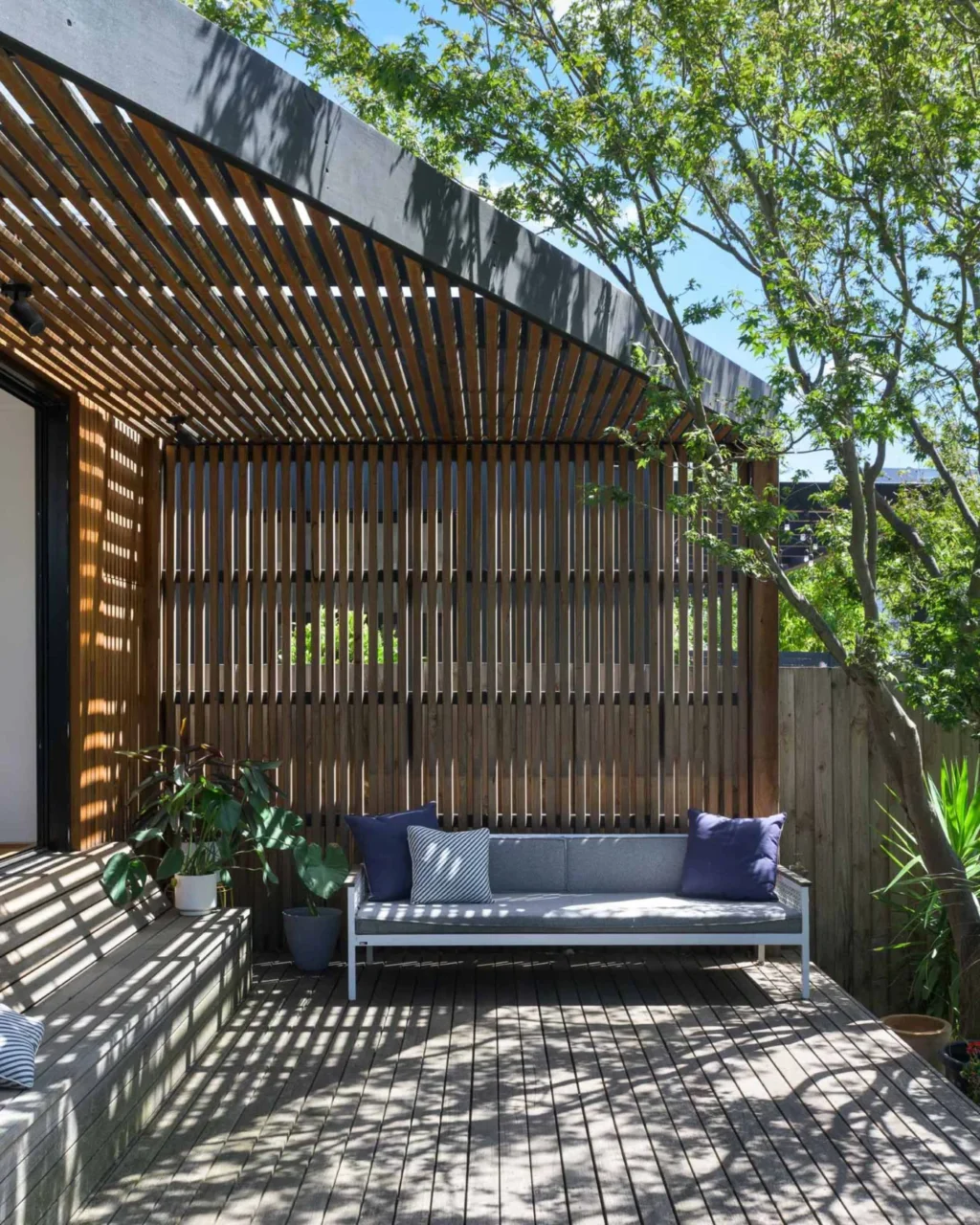 Outdoor couch beneath a slatted timber screen on the deck