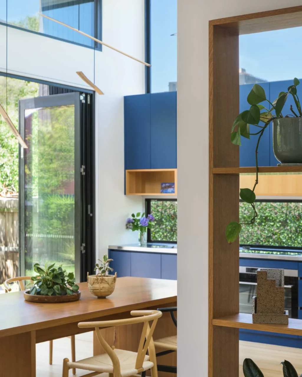Dining table and wood shelving beside blue kitchen cabinets