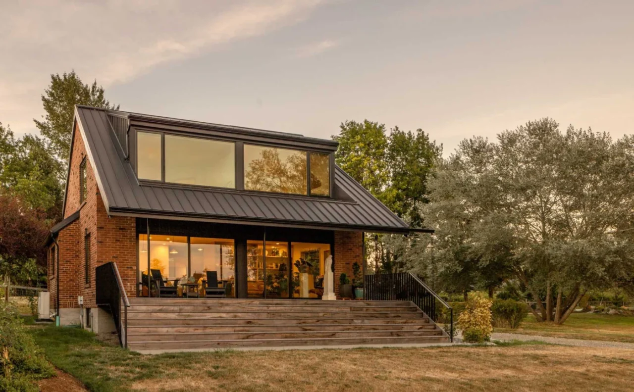 Sloping black metal roof and enlarged rear porch of the brick home
