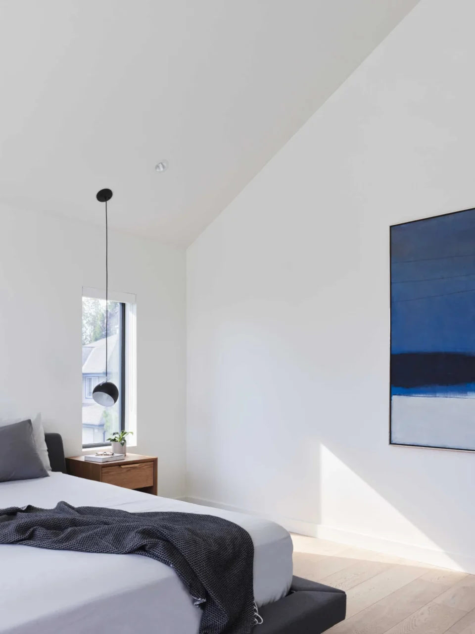 Bedroom with blue artwork and a pendant light used as a bedside lamp