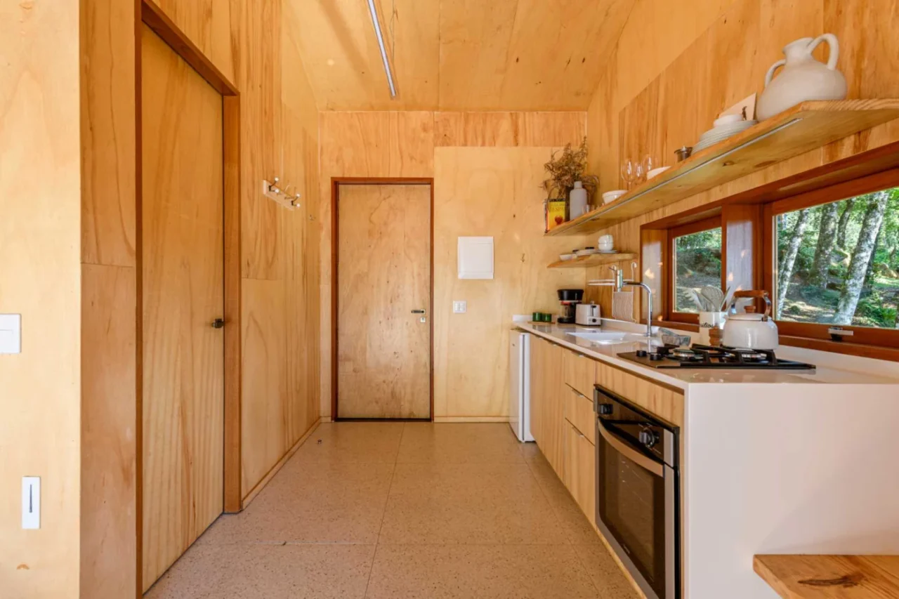Tree house kitchen with wood cabinets, white worktop and floating shelves