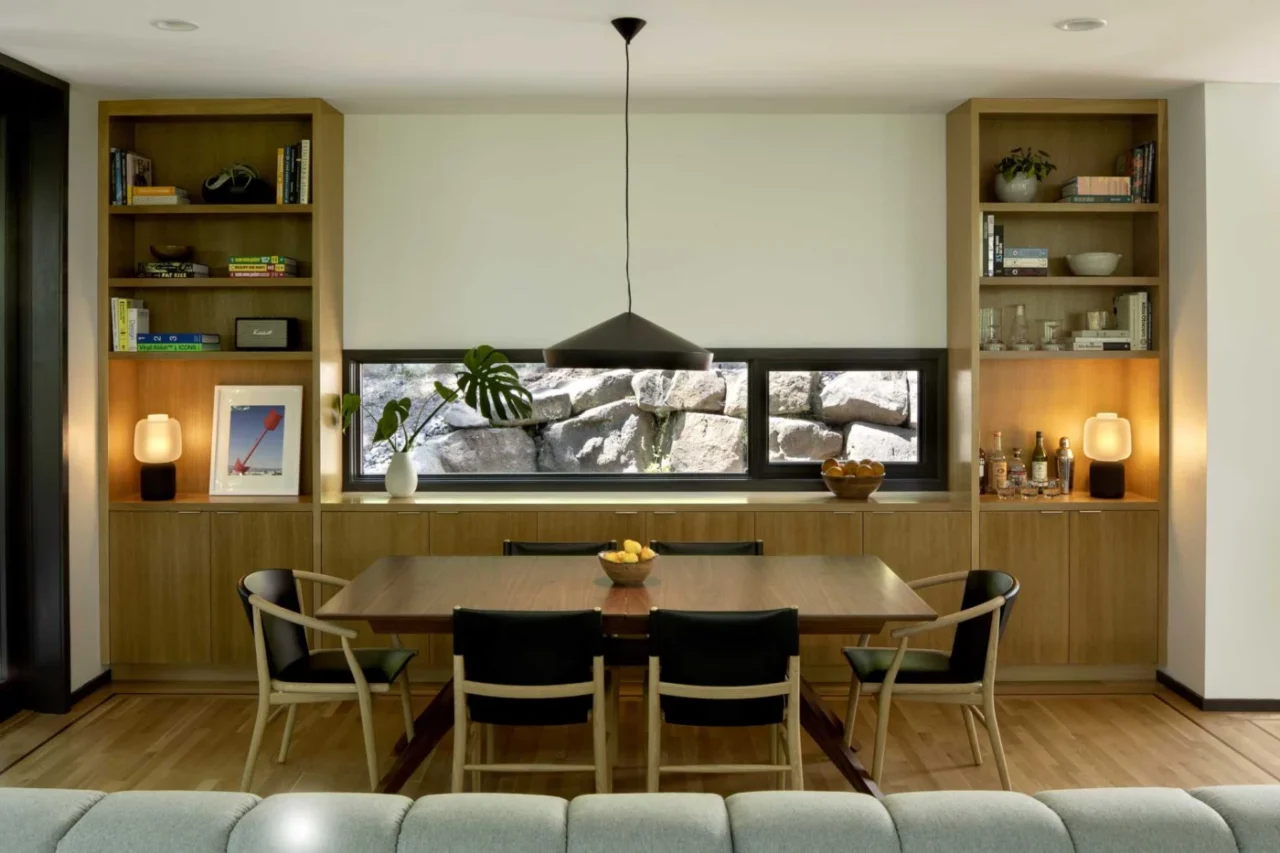 Dining area with a pendant lamp, oak and black leather chairs and custom shelving
