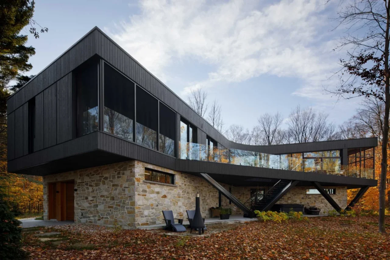 House in Mauricie, Québec, by Bourgeois / Lechasseur architectes, with a stone base and black upper floor