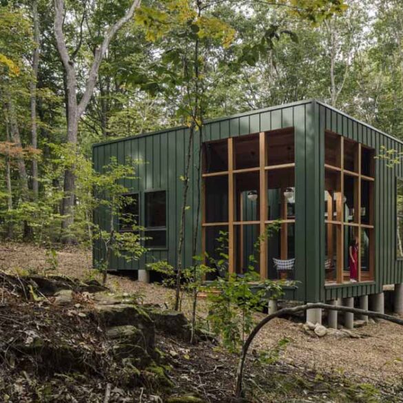 a-green-exterior-helps-this-cabin-blend-into-the-forest