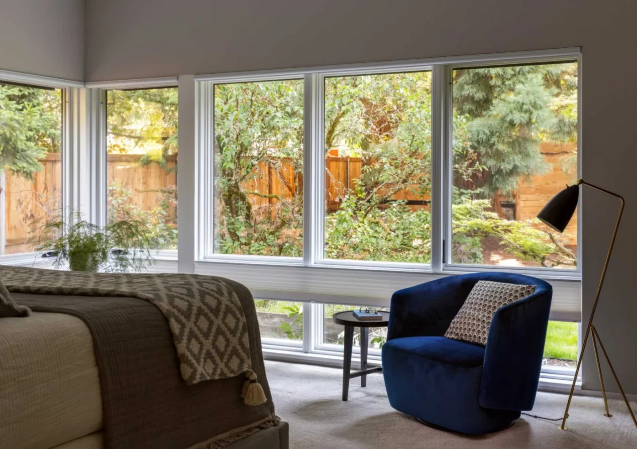 Bedroom with windows wrapping around toward the trees