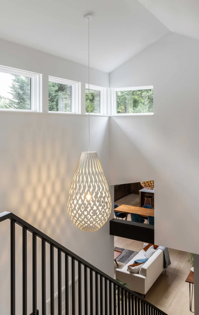 Stair to the addition with a sculptural pendant and a row of windows