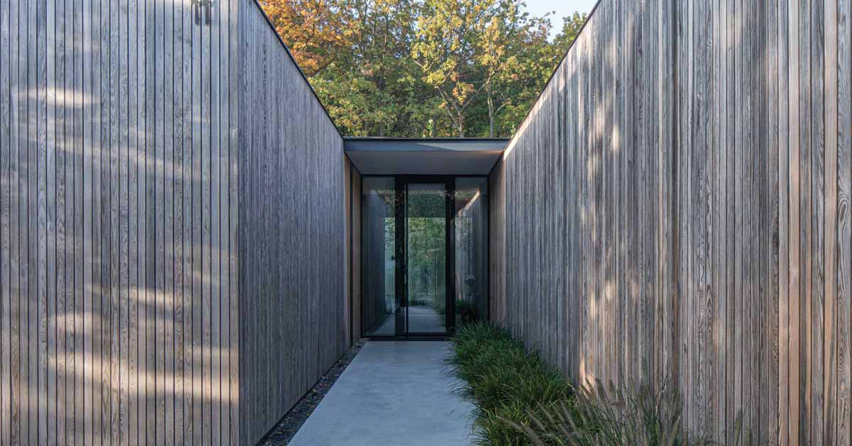 an-exterior-of-vertical-wood-siding-helps-this-house-blend-into-the-surrounding-forest