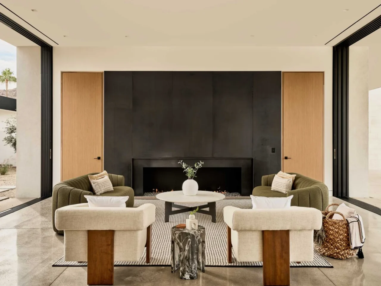 Great room with a large steel-clad fireplace and neutral furnishings