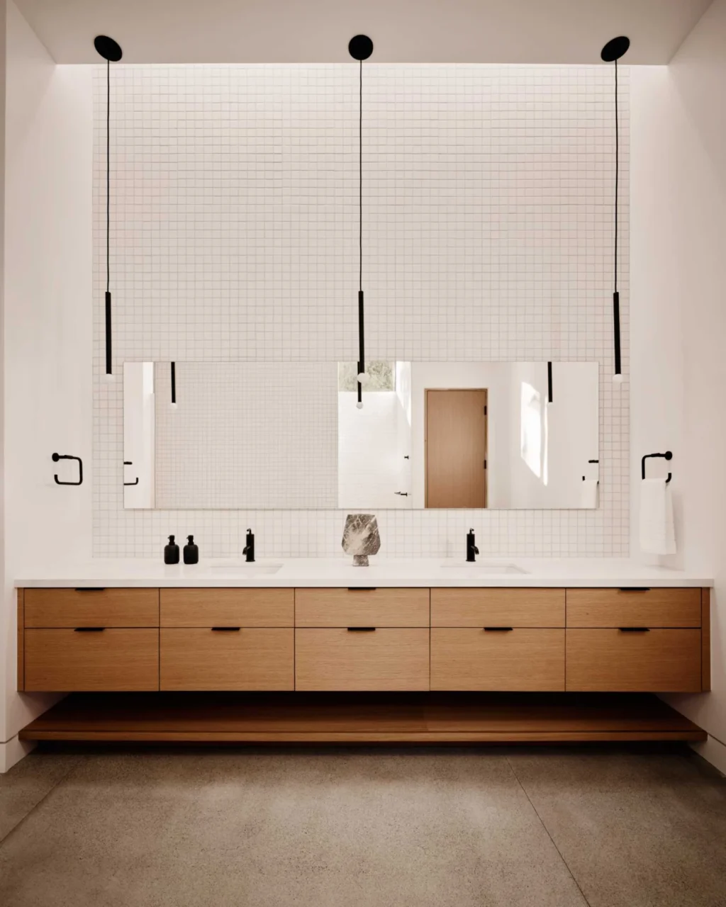 Tiled bathroom with black pendant lights and a long wood vanity
