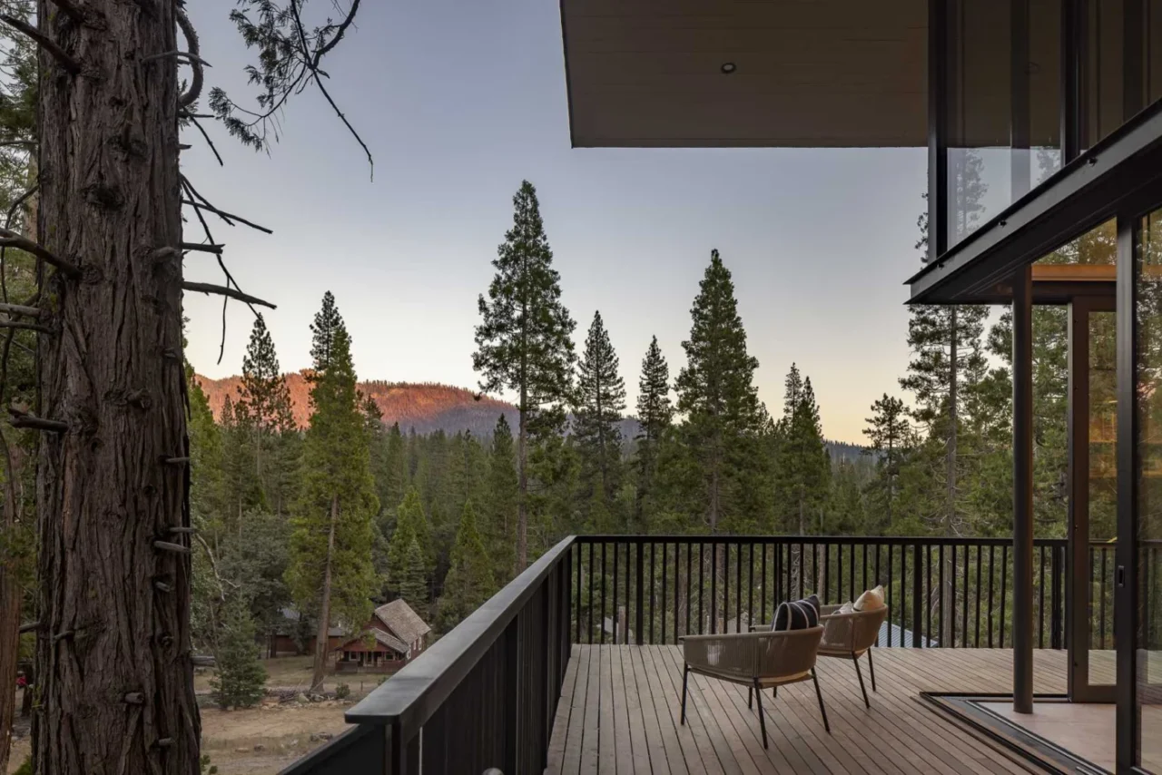 Wraparound deck with pickets in the same wood as the siding and a black railing