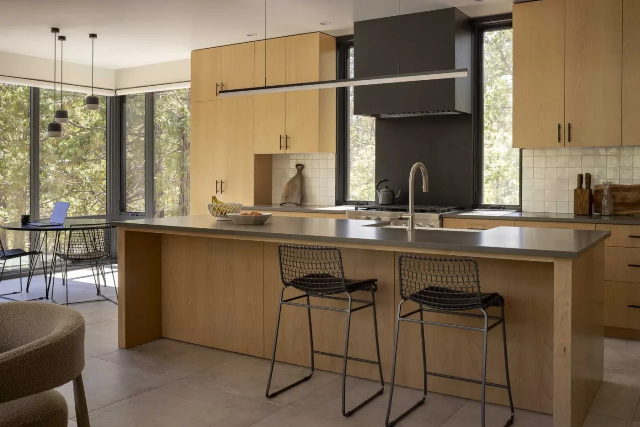 Open-plan kitchen with Beech Veneer cabinets, grey quartz countertops and a dining area by the windows