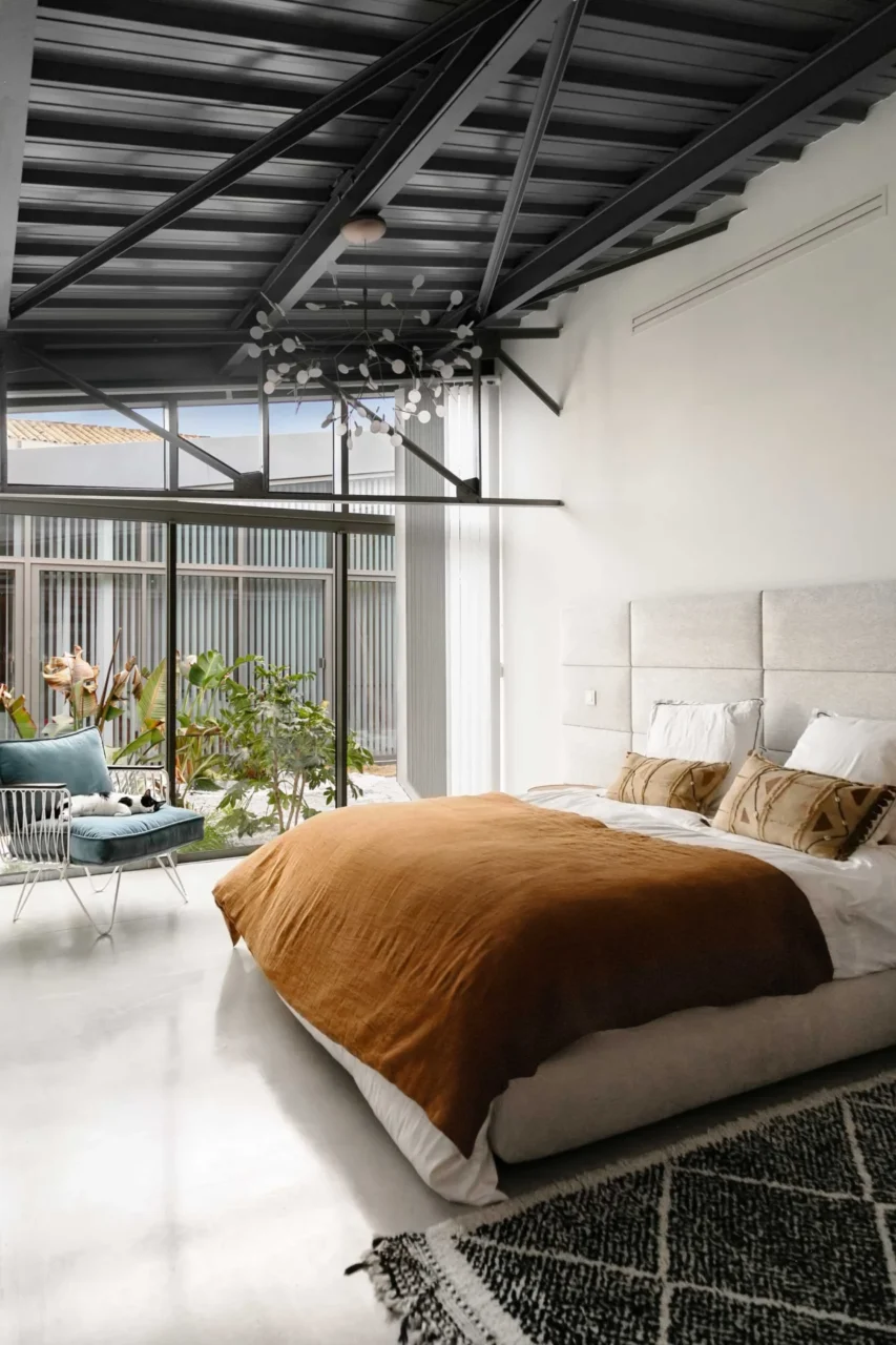 Bedroom with white walls, black elements and windows onto plants outside