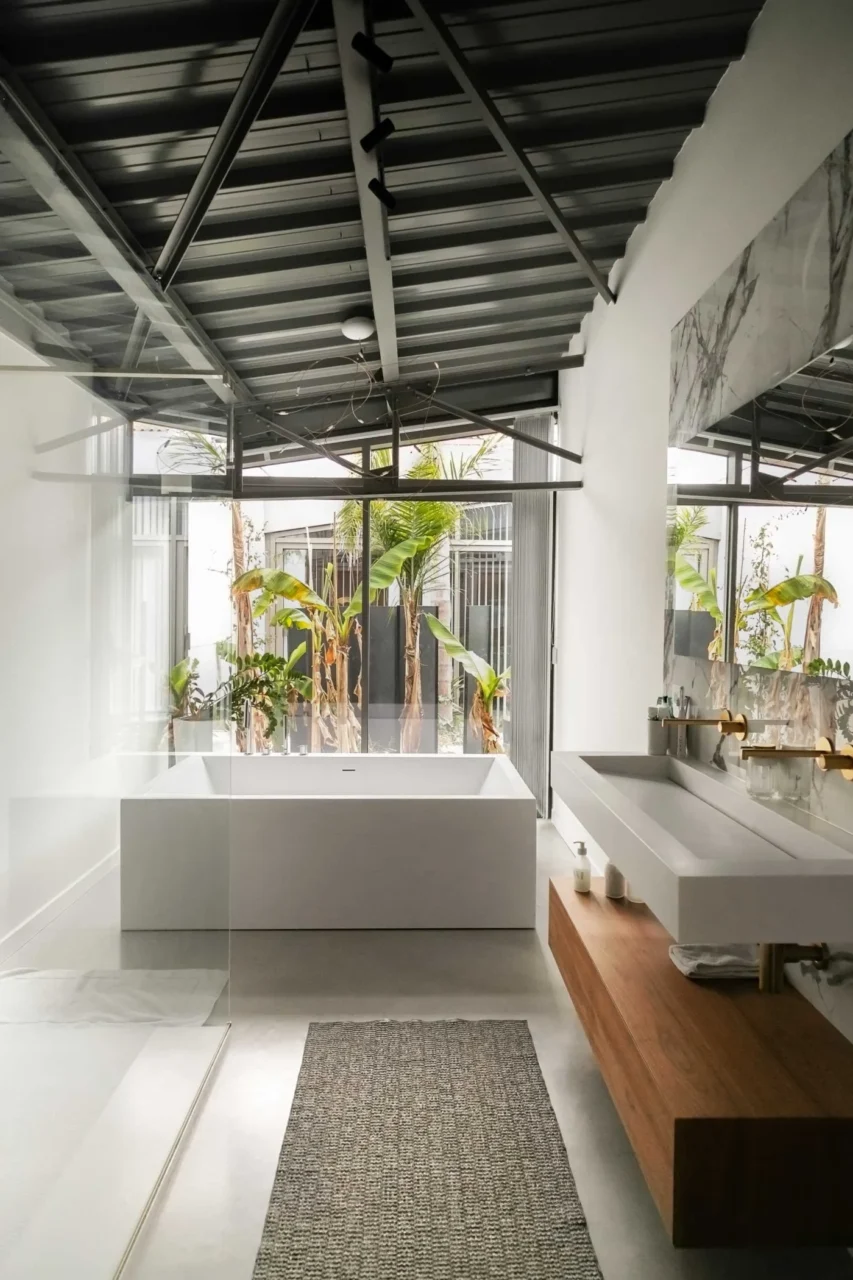 Bathroom with a freestanding white bathtub in front of windows and a wood shelf