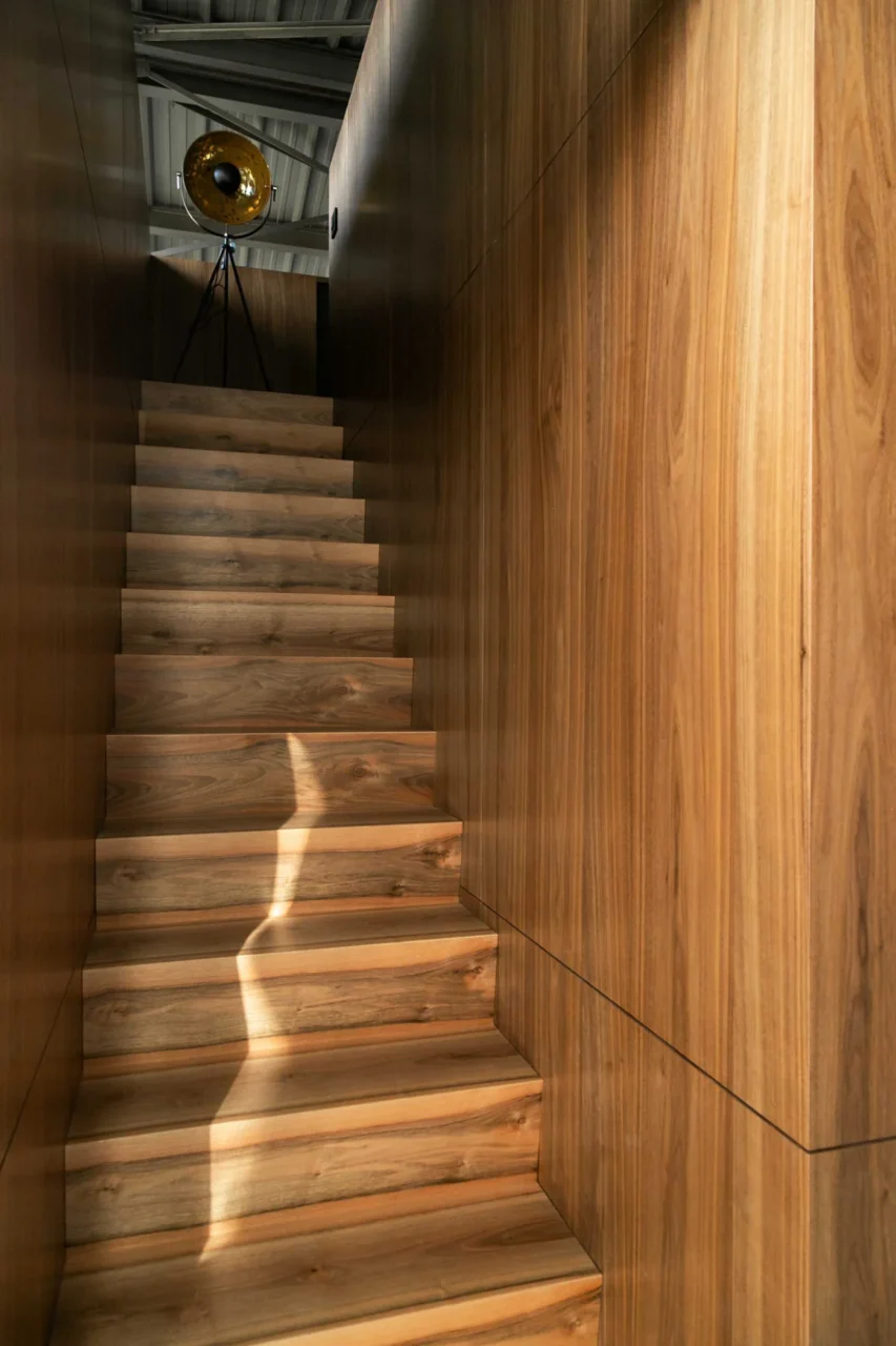 Wood stairs leading to a mezzanine on top of a walnut-clad box
