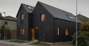 the-black-exterior-of-this-home-leads-to-a-pink-kitchen-inside