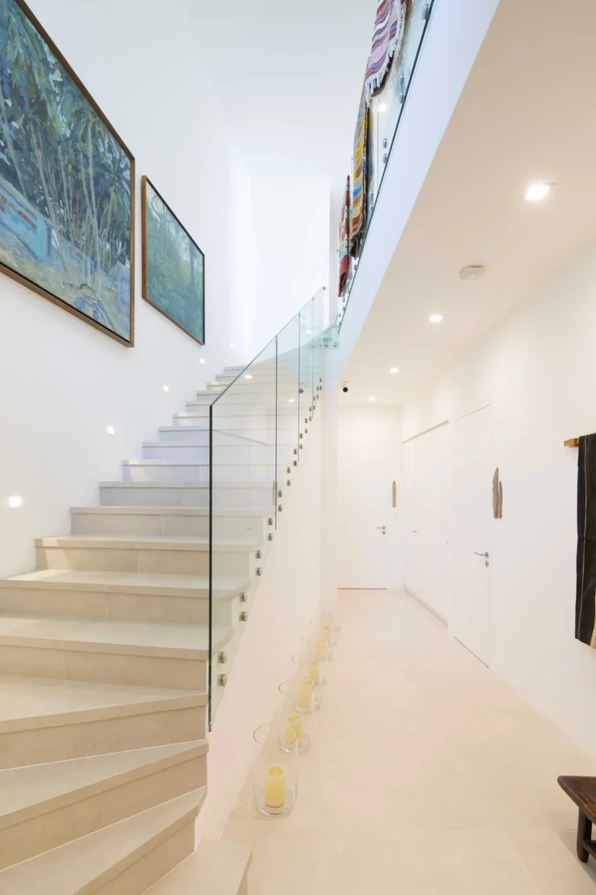 Staircase with a glass railing, artwork and rugs