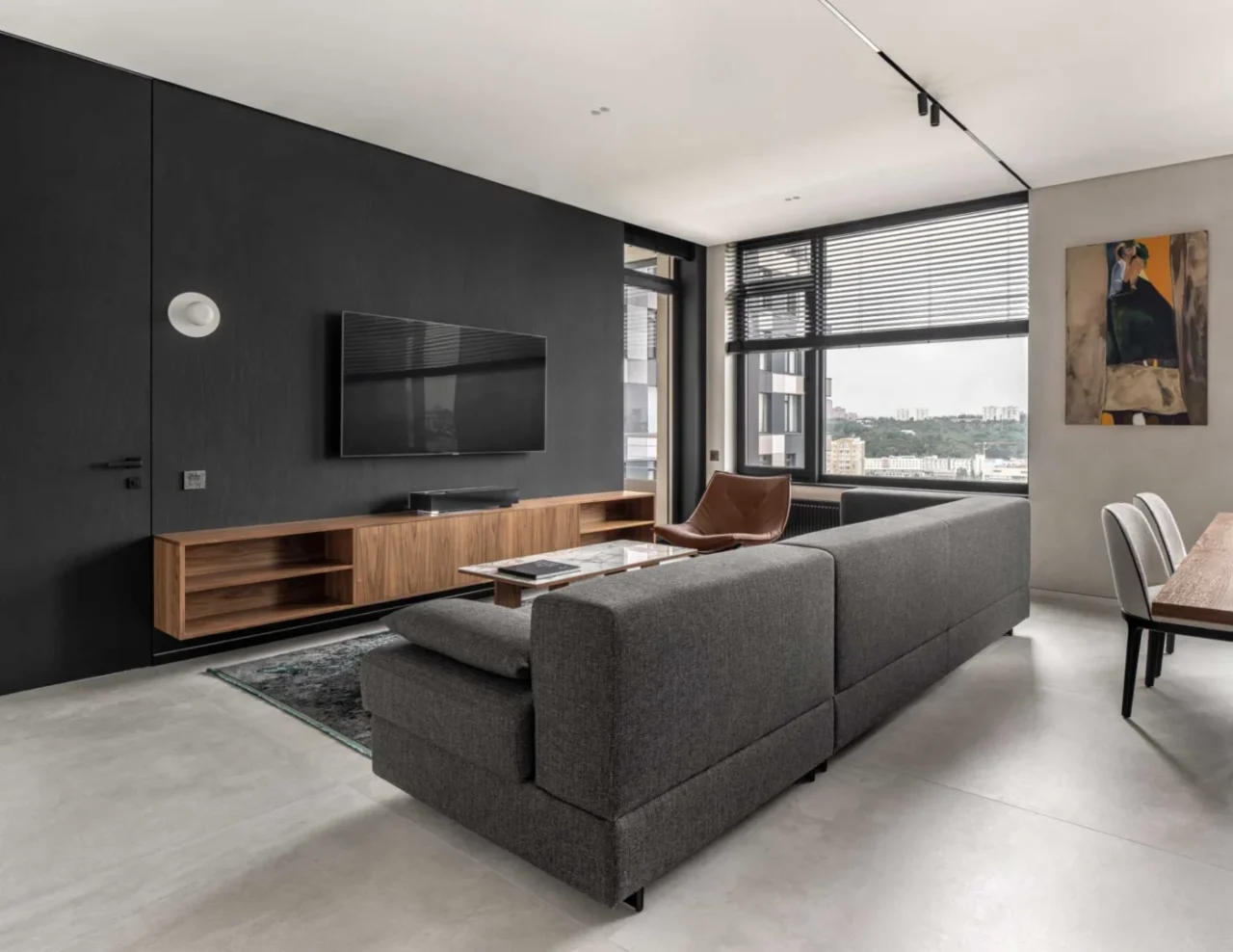 Living room with a dark accent wall, a large couch and a suspended cabinet with the TV above