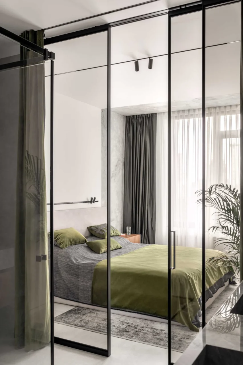 Master bedroom with black curtains, lighting and a chair