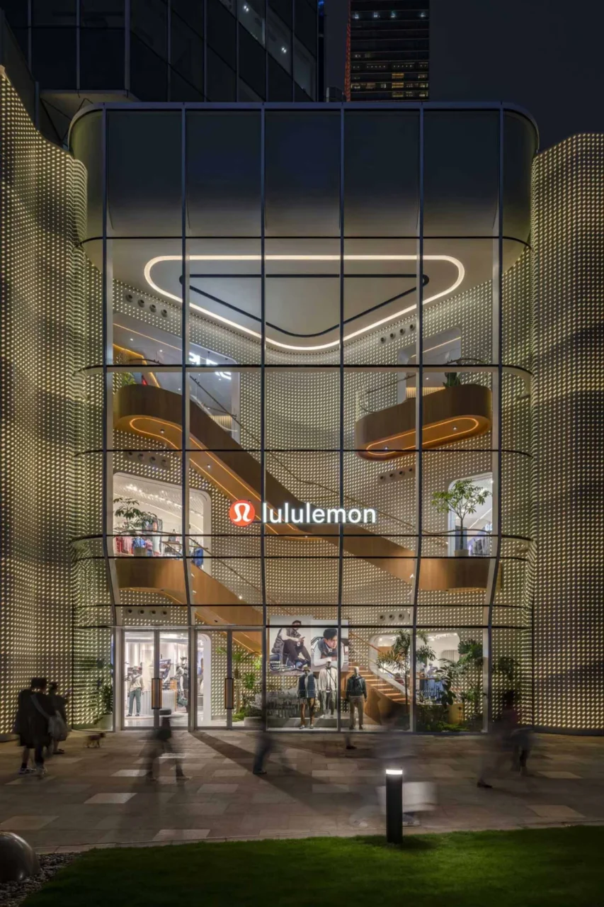 Lululemon flagship glowing at night, showing the staircase and several floors