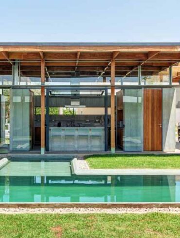 an-exposed-structure-shows-off-this-house-design-that-wraps-around-a-pool