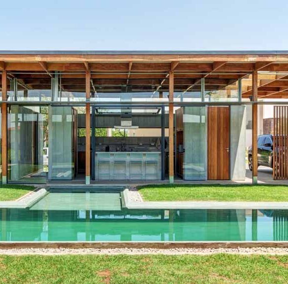 an-exposed-structure-shows-off-this-house-design-that-wraps-around-a-pool