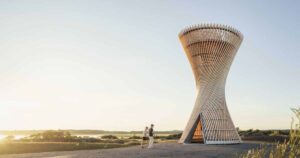 an-observation-tower-that-looks-like-twisted-wood-rises-above-the-swedish-landscape